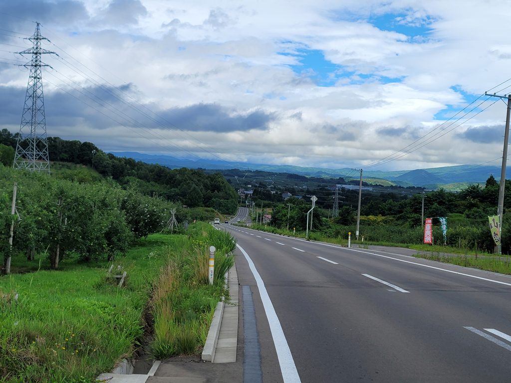 青森県弘前市両側にリンゴ畑が広がる弘前アップルロード。まっすぐ続く爽やかな道が先まで見渡せる