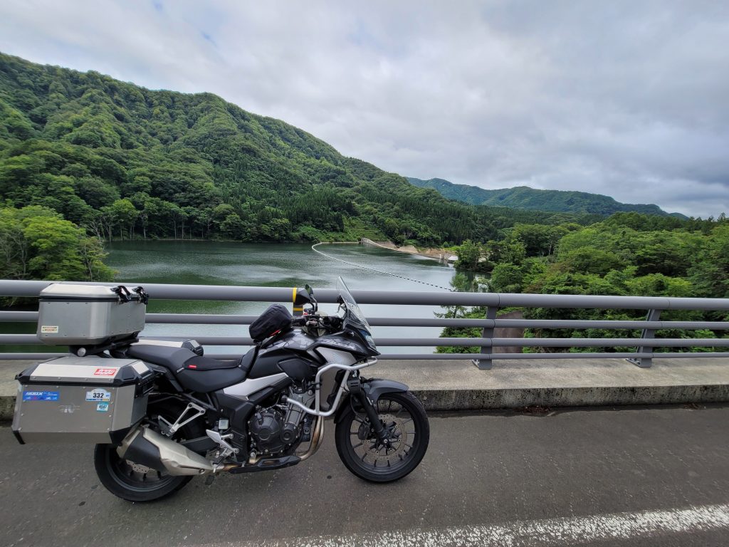 青森・津軽ダムのダム湖を前に、愛車と並んで撮影した様子
