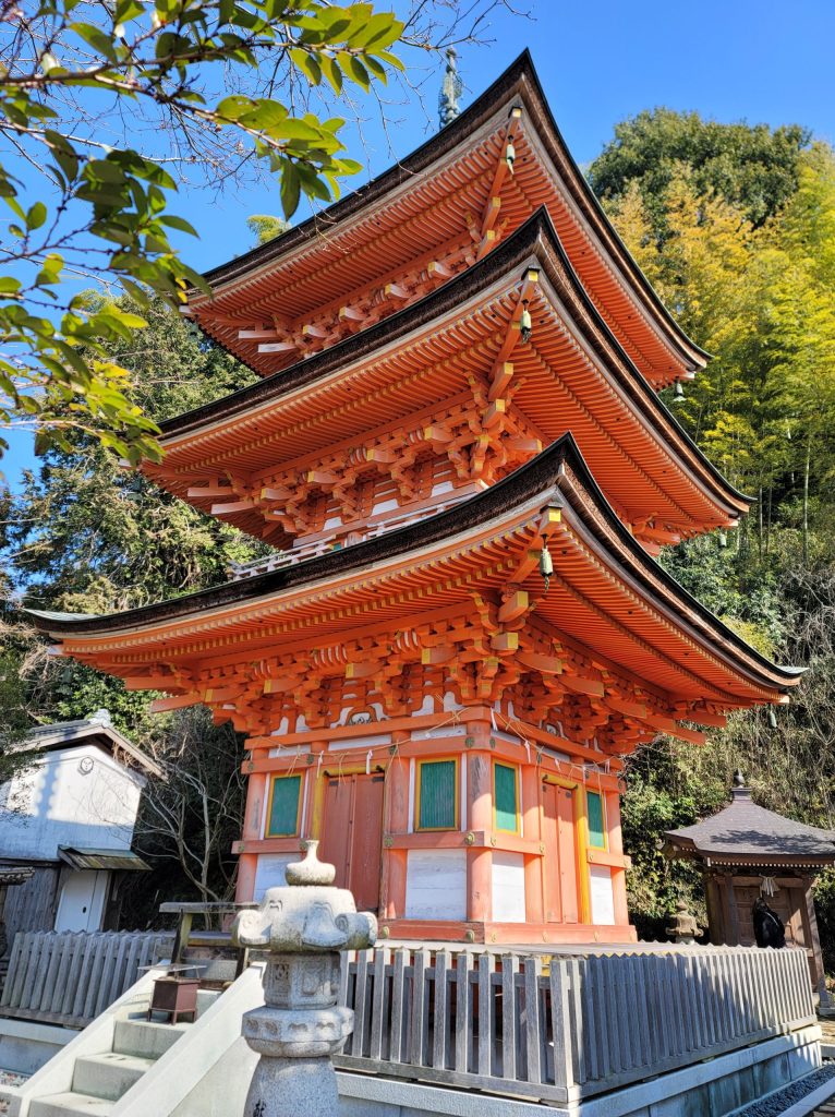 竹生島の宝厳寺にある朱色の三重塔の外観。緑の木々を背景にした鮮やかな朱色の塔。