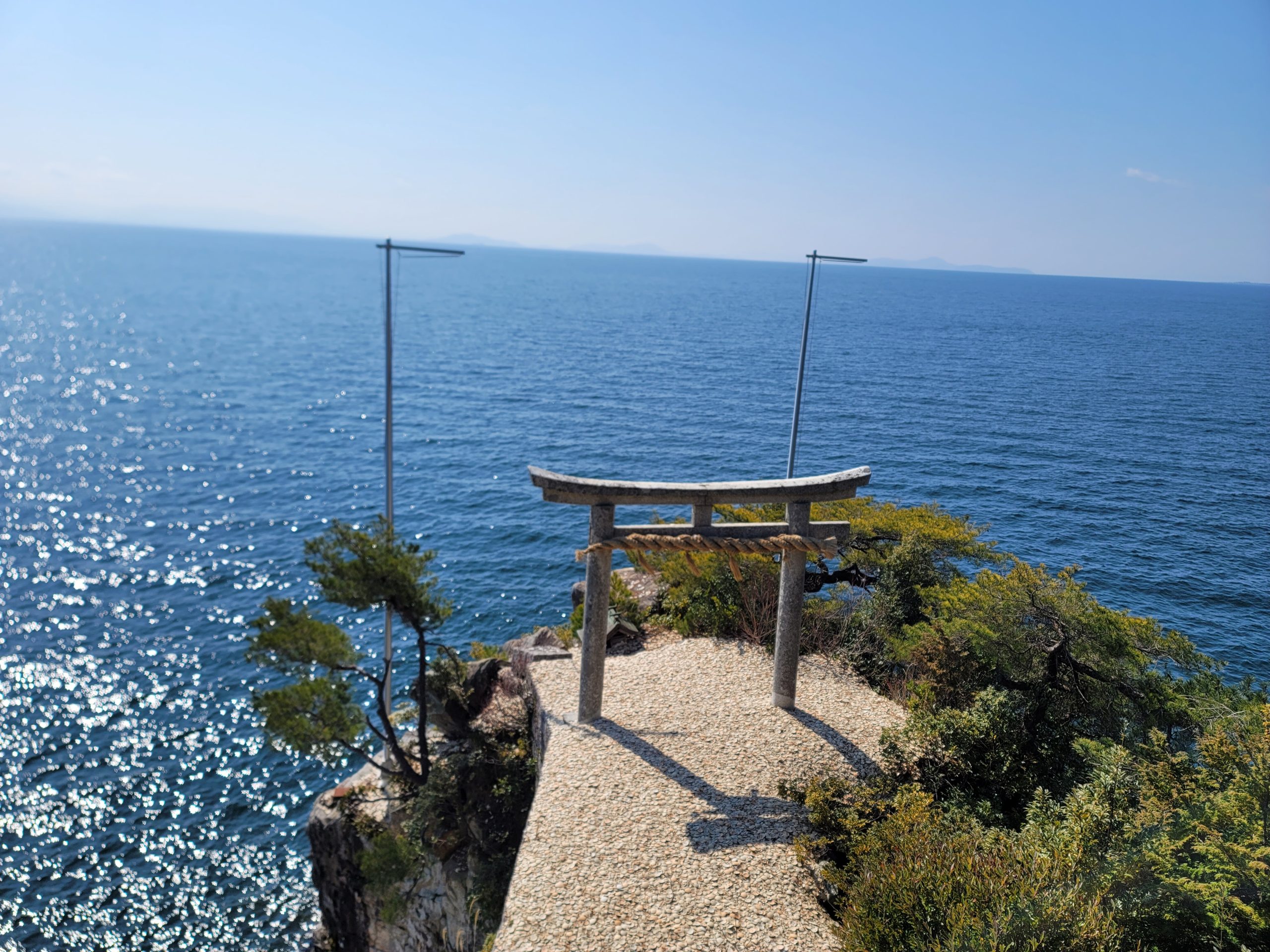 竹生島の竜神拝所で行われるかわらけ投げの様子。輝く琵琶湖を背景にした神聖な光景。