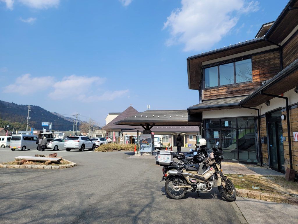 道の駅くつき新本陣の駐車場に停められたハンターカブと周囲の風景
