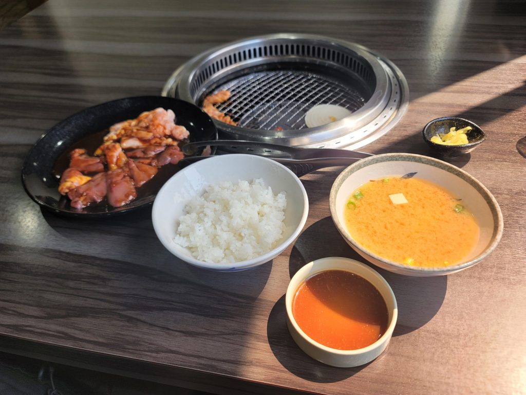 鈴鹿のとり焼き店『ふじがおか』で、ご飯セットの肉をテーブルの網で焼いている写真
