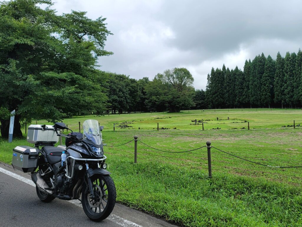 秋田県の大湯環状列石の横に停めたバイクと記念写真。ツーリング途中に偶然立ち寄り、史跡のスケールに圧倒された様子。