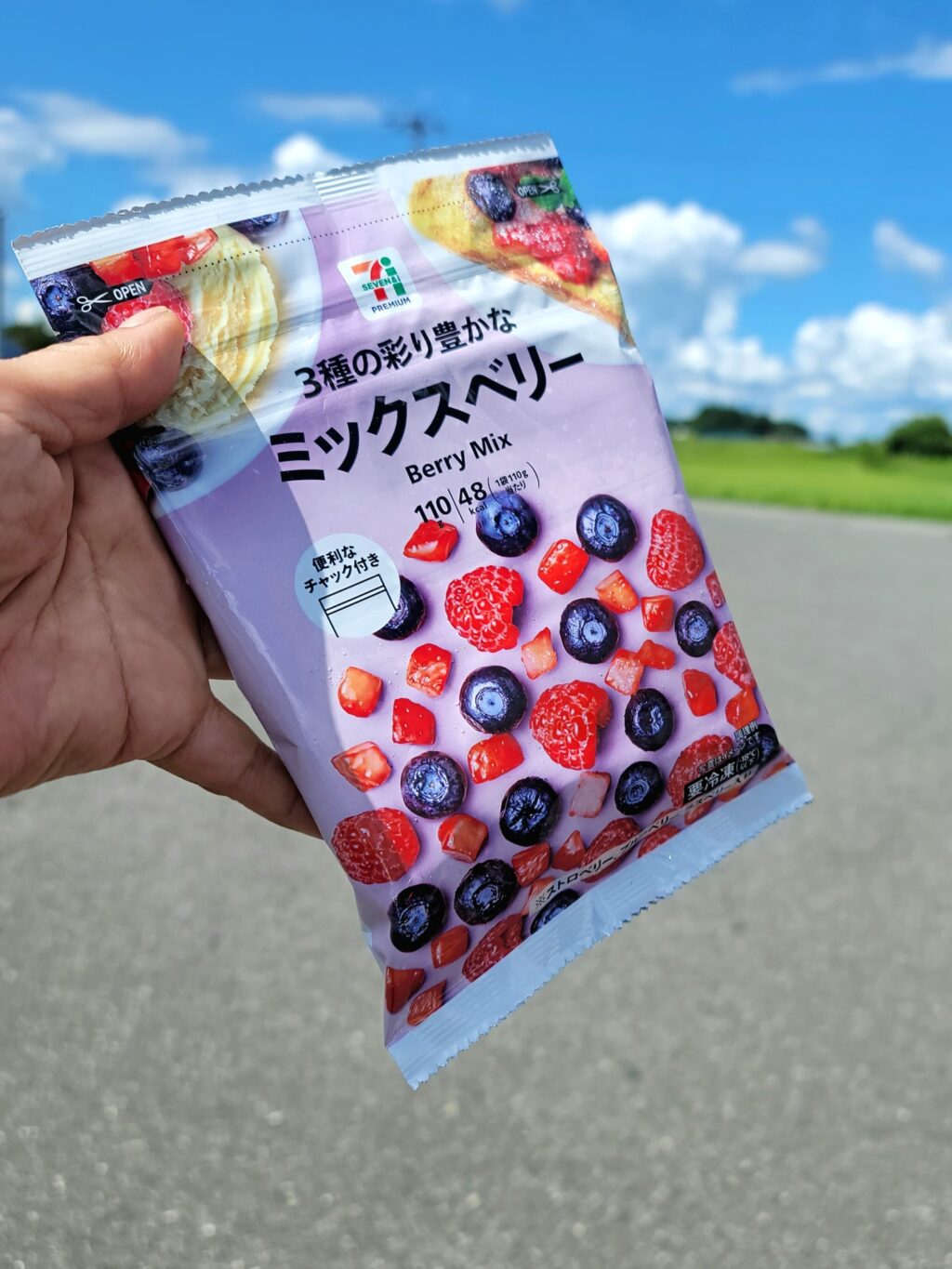 セブンイレブンの冷凍ミックスベリーを手に持つライダー。夏のツーリングで、ソフトクリームばかりにならないようビタミン補給している様子。