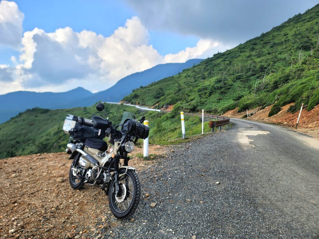 毛無峠のダート入口で停めたハンターカブと記念撮影している写真。
