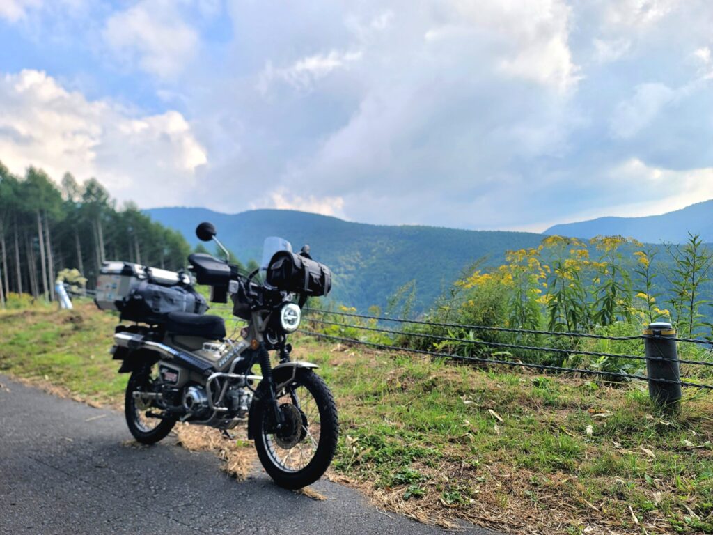 毛無峠の林道で、ハンターカブを停めて記念撮影。峠へ向かう林道ツーリングの風景と開けた景色を捉えた写真。
