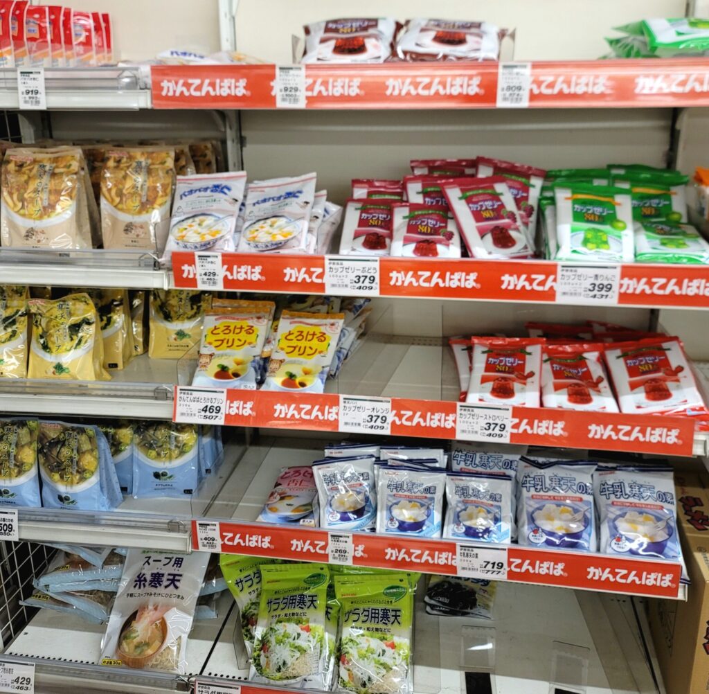 白馬のスーパーで、伊那食品の寒天プリン、ゼリー、寒天スープなどの商品棚がいっぱいに並んでいる写真。