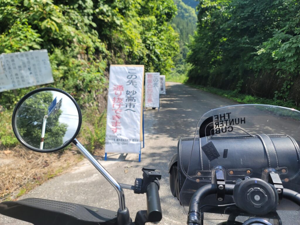 林道入り口の「通行可能」看板前に停めたハンターカブの写真。林道走行のスタート地点の雰囲気を伝えるショット。