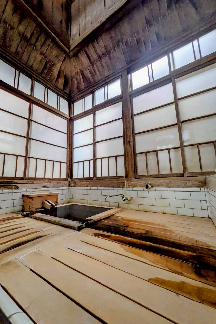 長野、渋温泉のつばたや旅館の家族風呂。檜の壁と木の洗い場に囲まれた、一人用にちょうどよい湯舟がある風情ある浴室