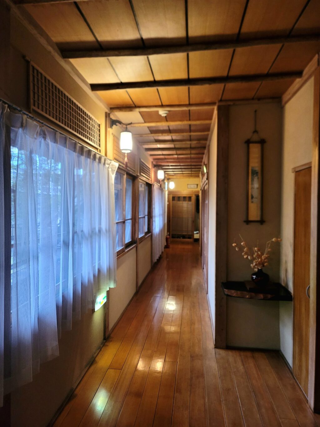 渋温泉つばたや旅館の2階廊下。生け花や掛け軸が飾られた趣ある和風の空間