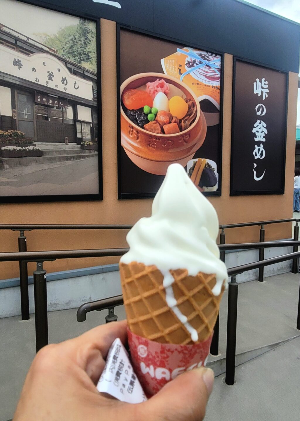 湯の丸高原サービスエリアの峠の釜めし「おぎのや」や前で、手にソフトクリームを持つ主婦ライダー