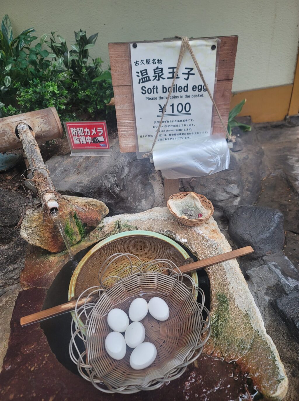 長野・渋温泉・古久屋旅館前にある温泉井戸風の設備で、温泉卵が浸けられている様子。セルフで料金を入れて購入できる。