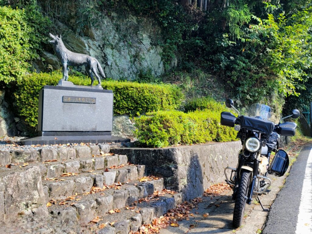 奈良県東吉野村にある日本オオカミの石碑とハンターカブを並べて撮影した写真。山奥ツーリングならではの一枚