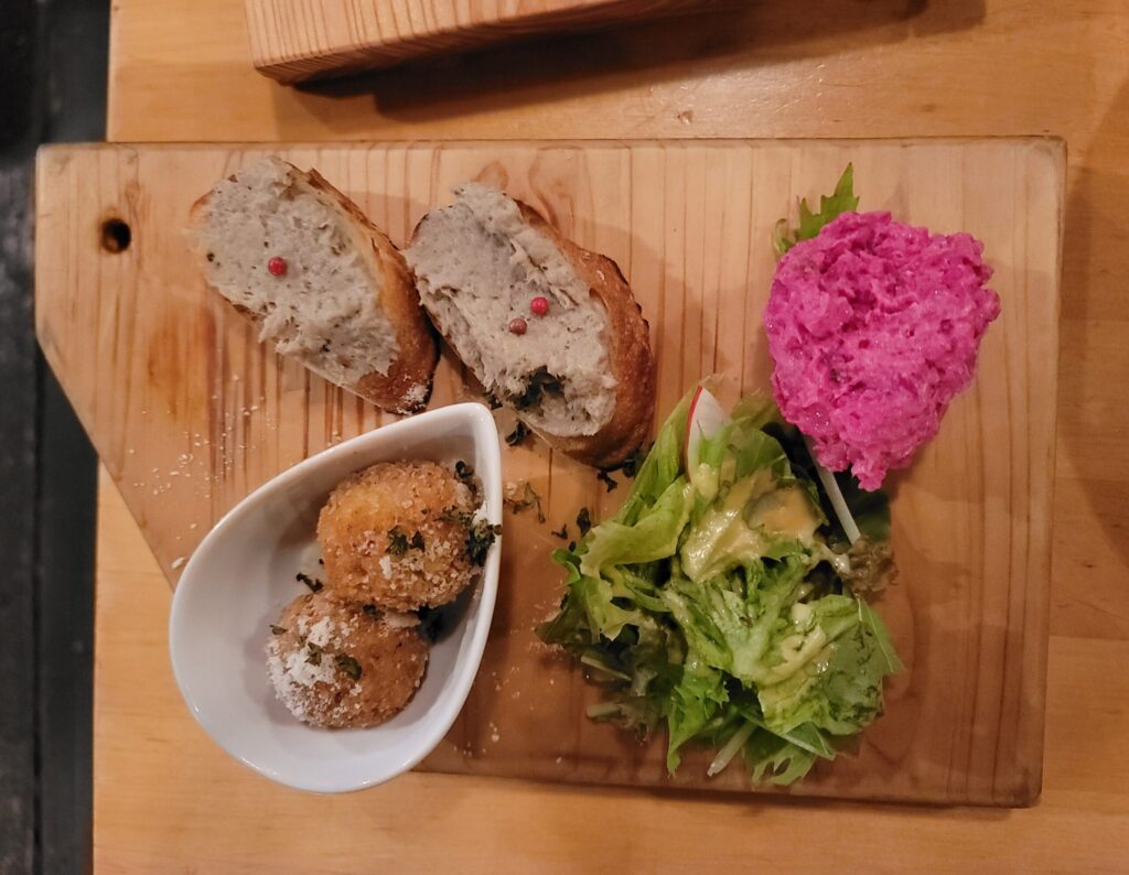 長野・白馬のレストランTomatitoで提供された前菜プレート。ライスコロッケ、ビーツのポテトサラダ、グリーンサラダ、サバのリエットなどが美しく盛り付けられている