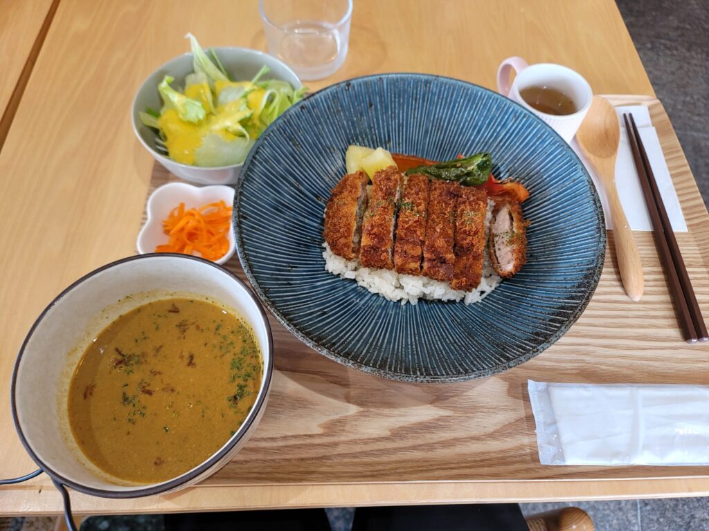 長野県、東御市。しなの鉄道・田中駅近くの「ゆーぷる田中」内にあるとうみ食堂で提供されるスープカツカレー。
信州黄金シャモの旨みを凝縮したスープに、こうじいらず大豆味噌のコクを加え、
季節野菜とサクサクのカツを合わせた心温まる一皿。