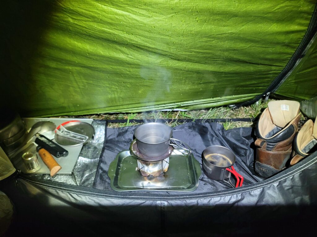 アルコールストーブでコーヒーを沸かす写真|テントの土間で過ごすソロキャンプの夜のひととき