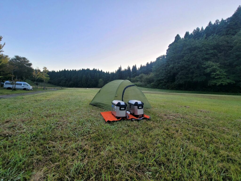 山形・庄内羽黒キャンプ場のフリーサイトの朝の風景。広い芝生にソロテントを張っている様子。