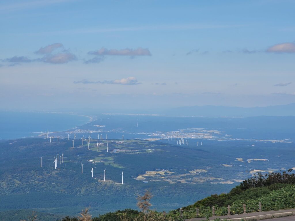 鳥海山・鉾立展望台から見た日本海と、仁賀保高原の風車群が並ぶ景色の写真