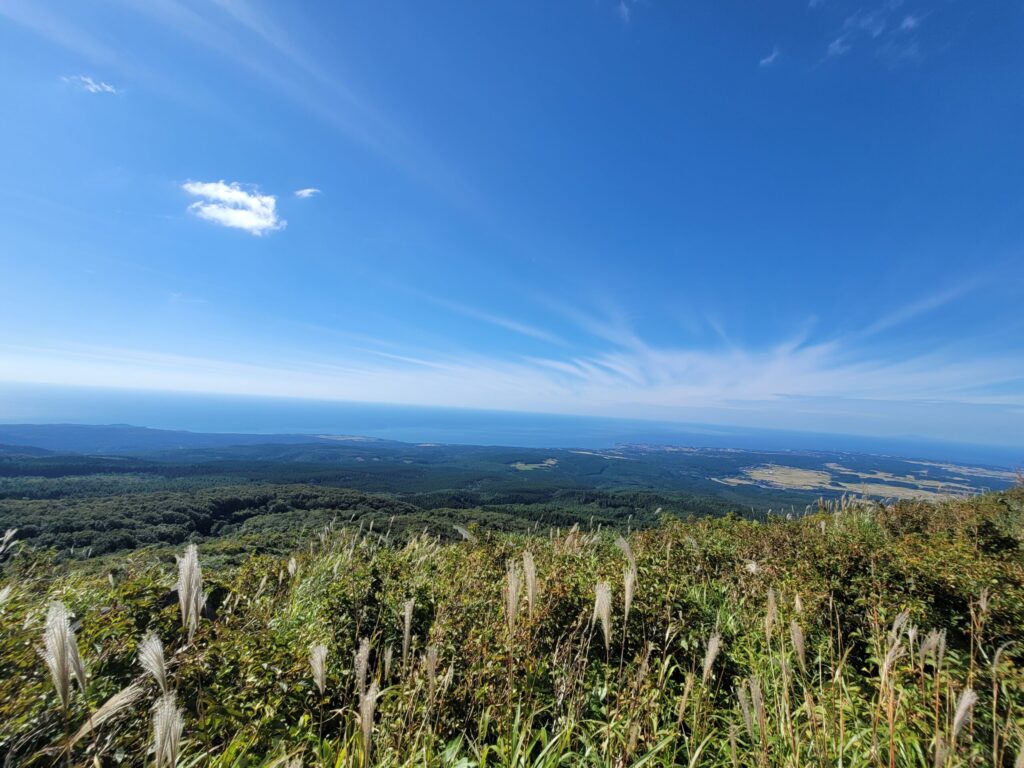 鳥海ブルーラインの展望地点から見える日本海と庄内平野の風景。空と海のグラデーションが美しい