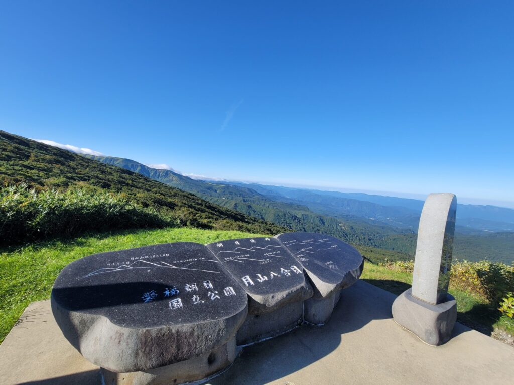 月山八合目の記念碑と、庄内平野や周囲の山々が一望できる美しい景色