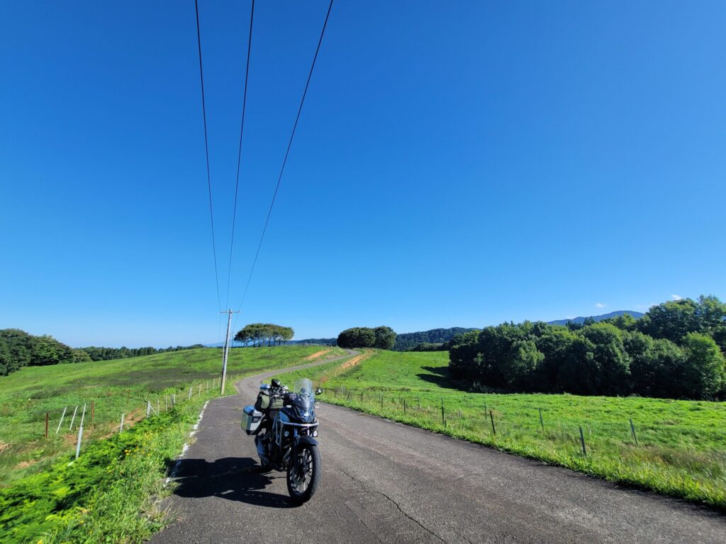 山形・月山高原牧場の農道に停めたHonda 400Xと、青空と高原が広がる風景