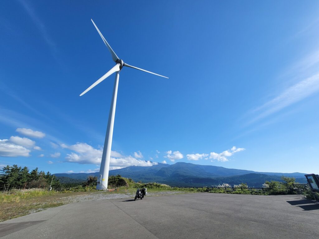 仁賀保高原の風車の下でHonda 400Xを撮影した写真。青空と草原が広がる風景