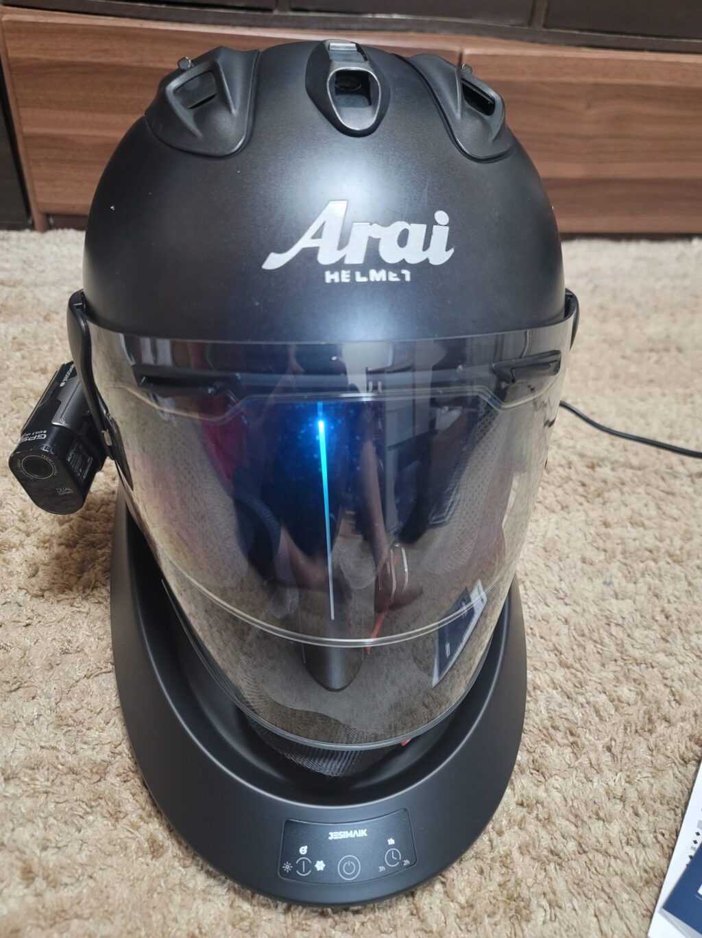 JESIMIAKヘルメット消臭乾燥機A2Sにヘルメットをのせ、電源を入れた状態。
稼働中はLEDランプが青・緑・赤と順に変化して光る。