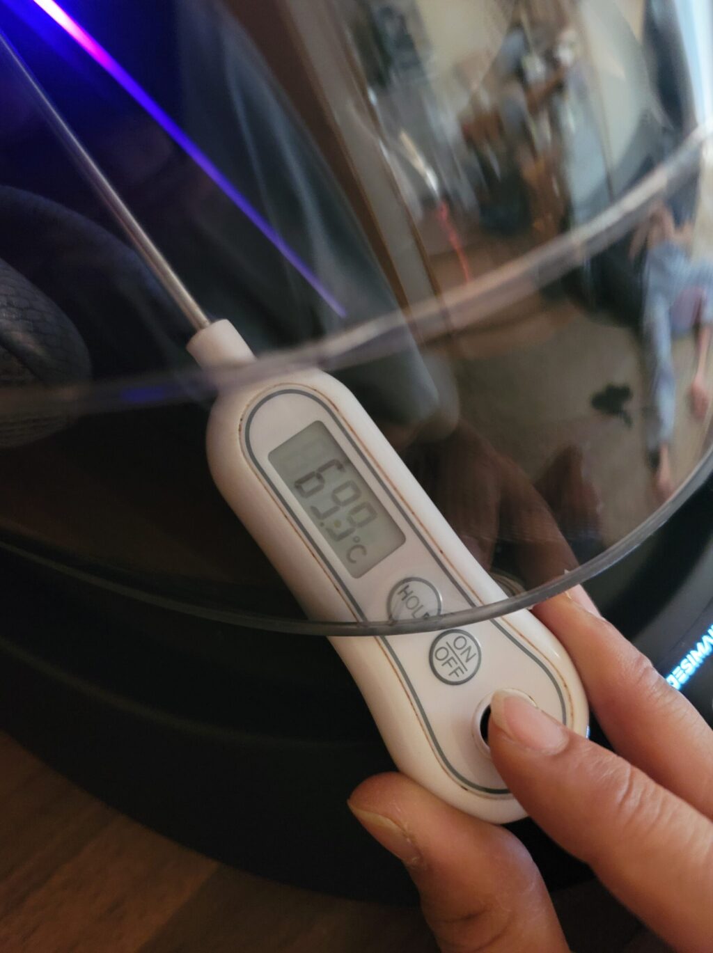 JESIMIAKヘルメット消臭乾燥機A2Sを温風モードに設定し、吹き出し口の温度を温度計で測定している様子。 実際の温かさを確認するために計測を行っている写真。
