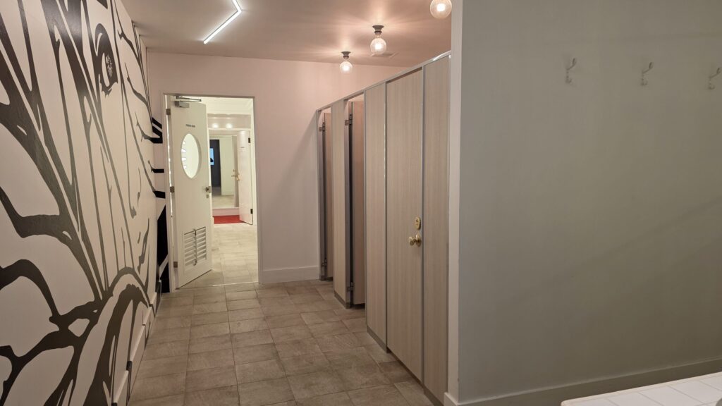 バイカーズパラダイスのトイレ入口と個室。白を基調とした清潔な内装