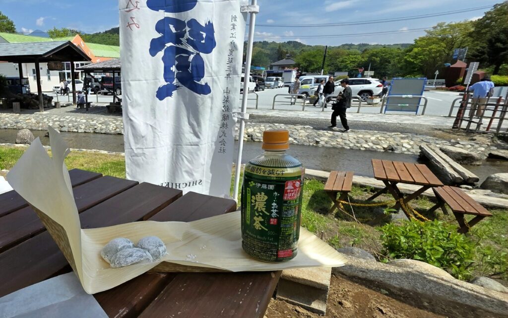 山梨県道の駅白州の外のベンチとテーブル。テーブルの上には笹子餅とお茶が載っている様子。