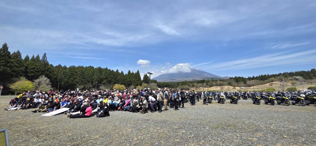 富士山子供の国のV-STROMミーティング会場でオーナーと愛車が勢揃いで集合写真を撮っている様子