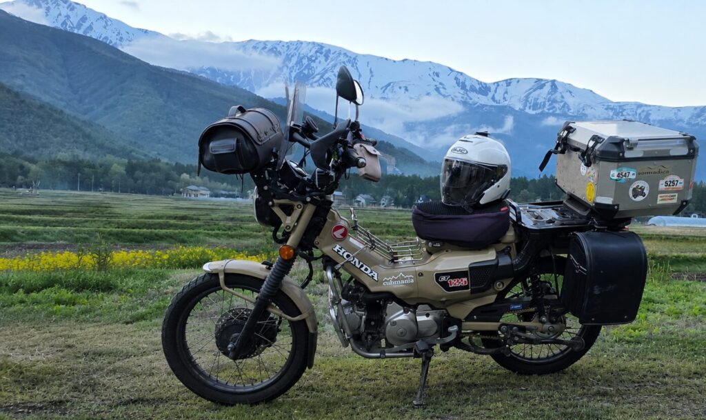 HJC i31ホワイトをCT125ハンターカブのシートに置き、北アルプスを背景に撮影したツーリング風景