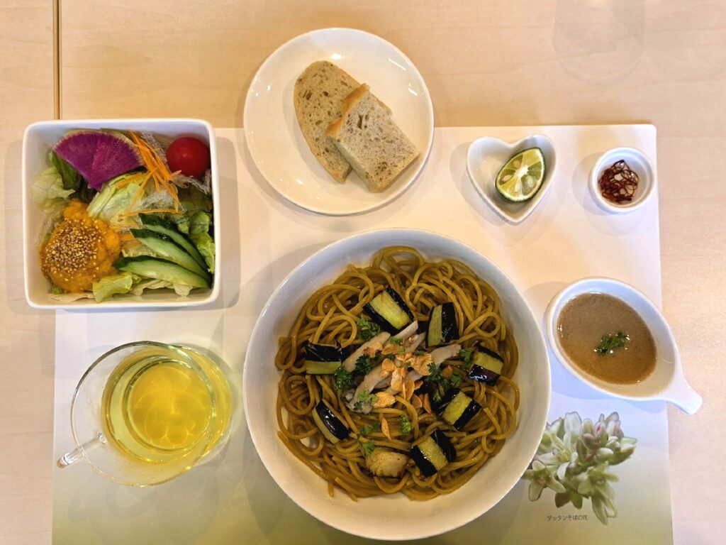 レストラン緑の花そば館の韃靼そばパスタのランチ。韃靼そば粉のパスタ、パン、サラダ、韃靼蕎麦茶が写っている様子
