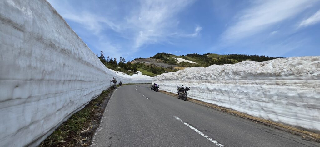 渋峠の雪の回廊とハンターカブ、他のバイクが写真撮影している景色