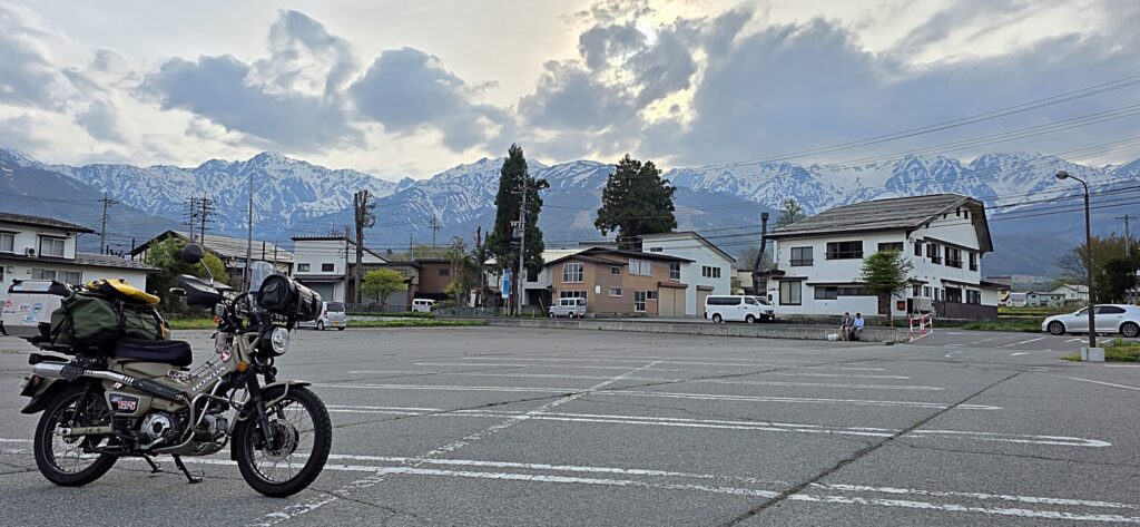 A-coop白馬店の駐車場とハンターカブ。遠くに残雪の北アルプスの絶景が見える