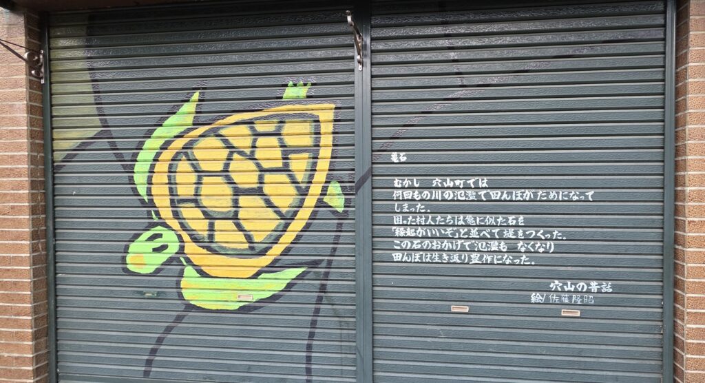 山梨県韮崎駅周辺の店舗のシャッターに描かれた絵。山梨の昔話の絵が描かれている