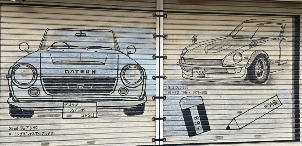 山梨県韮崎駅周辺の店舗のシャッターに描かれた絵。車屋さんらしく、車の絵が描かれている